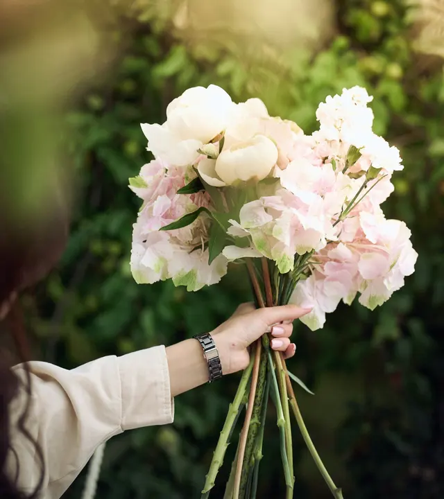 A hand holding a bouquet of pink and white flowers